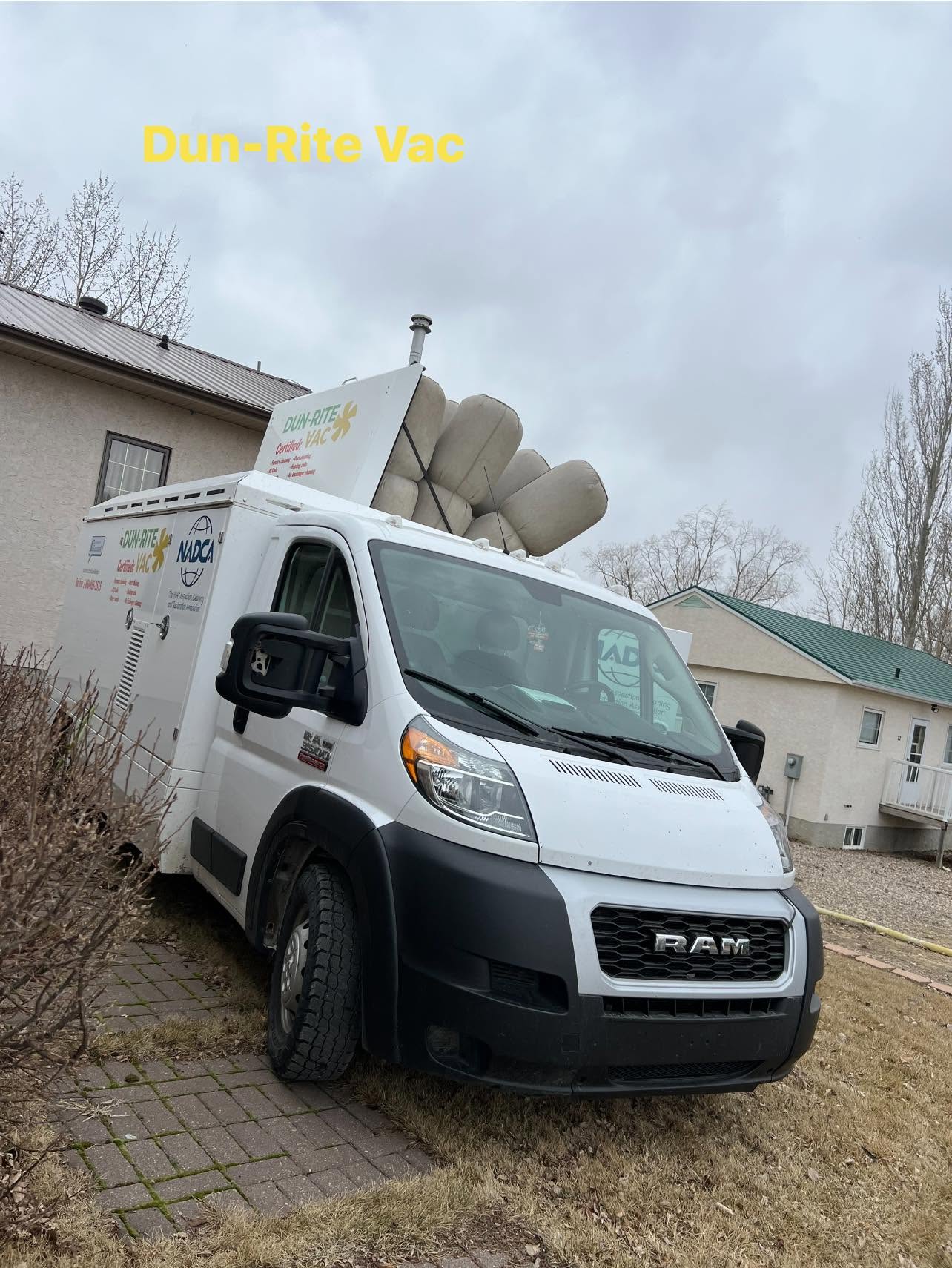 Dun-Rite Vac service van parked in a residential driveway with NADCA-certified duct cleaning equipment loaded on the roof